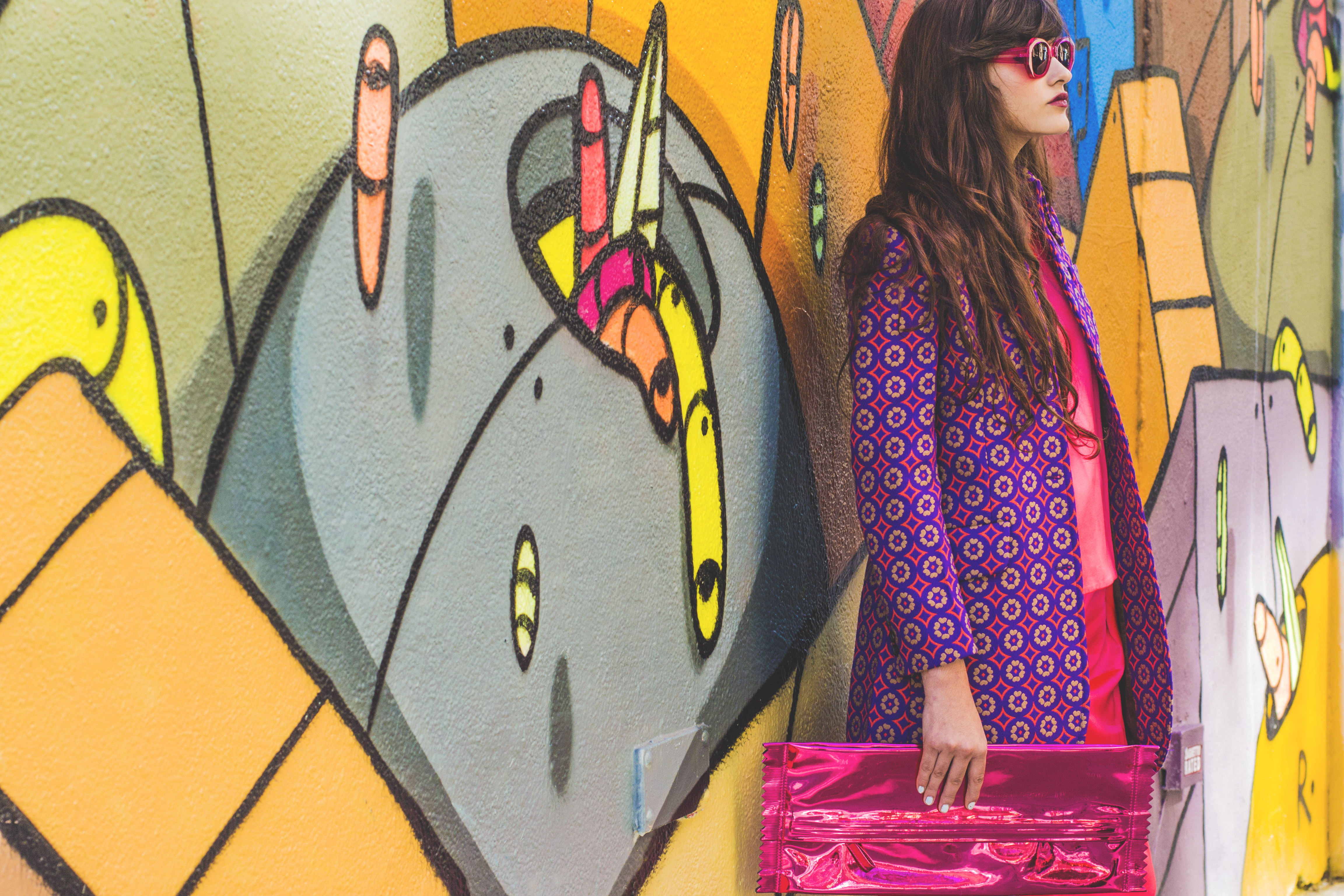 multicolored geometric print coat MIU MIU. fuchsia silk top and matching trousers LES CHIFFONIERS. fuchsia patent leather candy wrapper clutch MAISON MARTIN MARGIELA. red molded flower necklace J CREW. translucent pink sunglasses KAREN WALKER. 